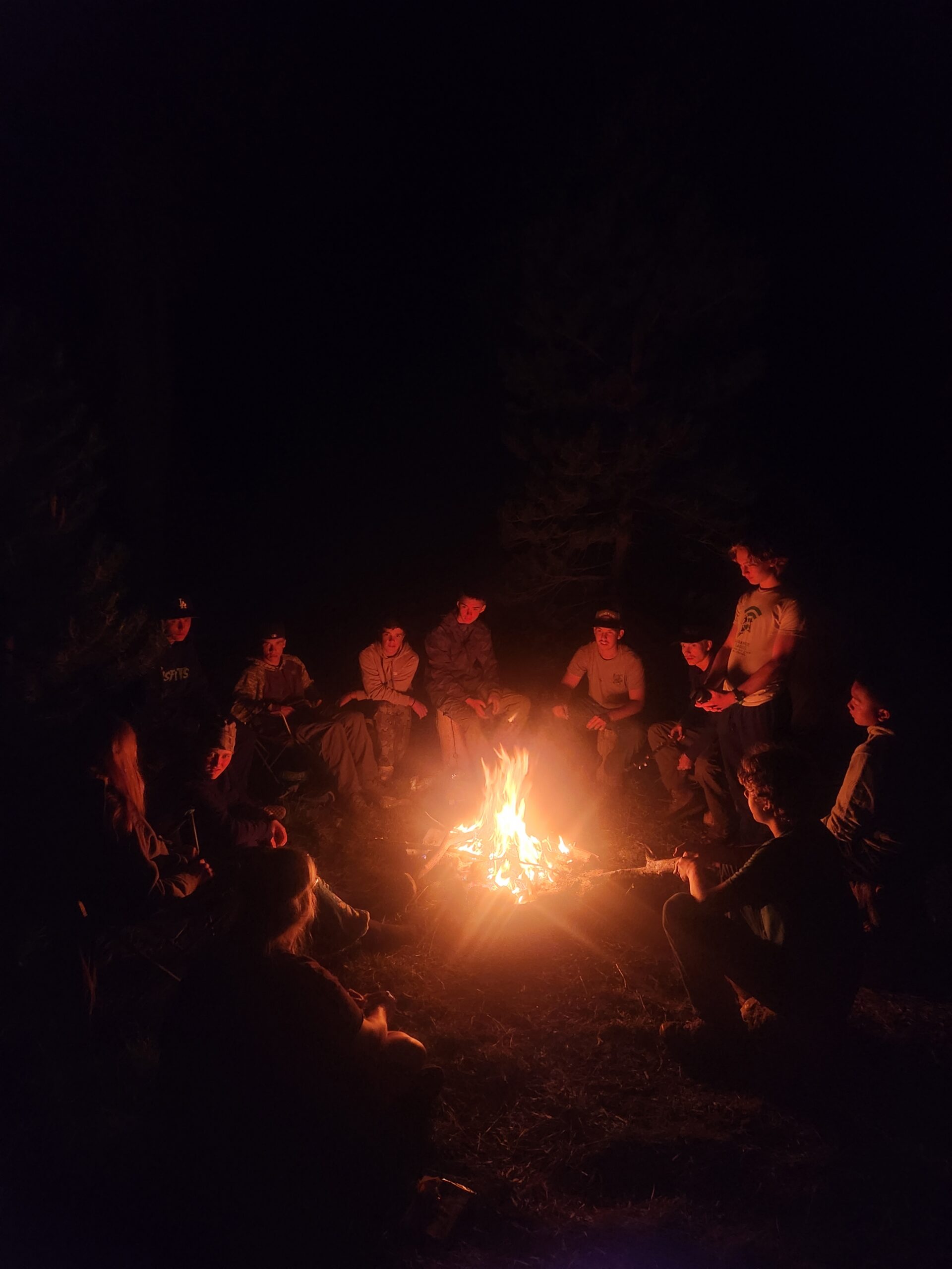 Ascend youth backpacking participants gathered around a campfire